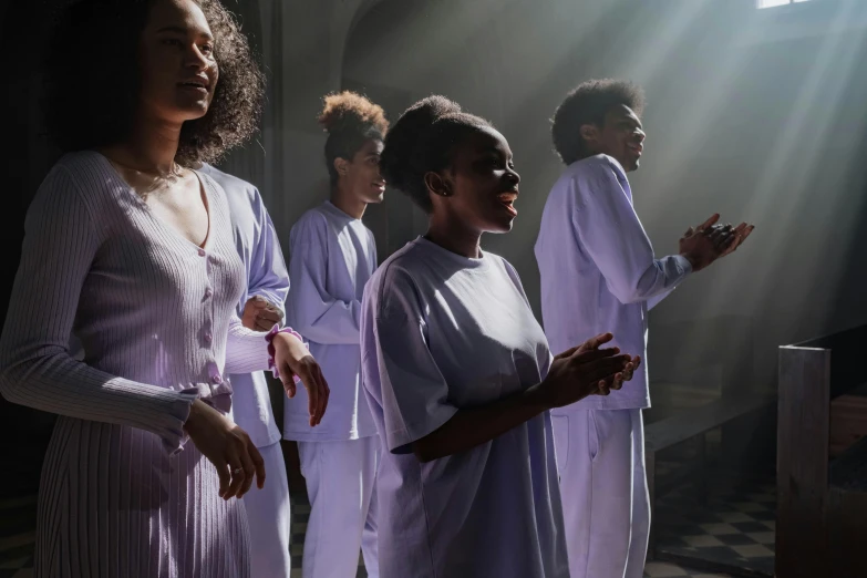 five women standing together in choir robes, with sun shining through the window