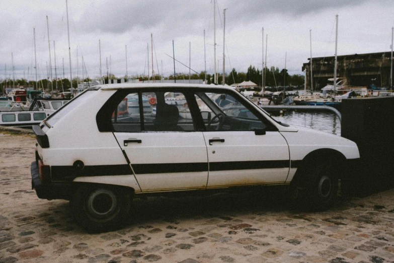 the white and black car is parked next to some boats