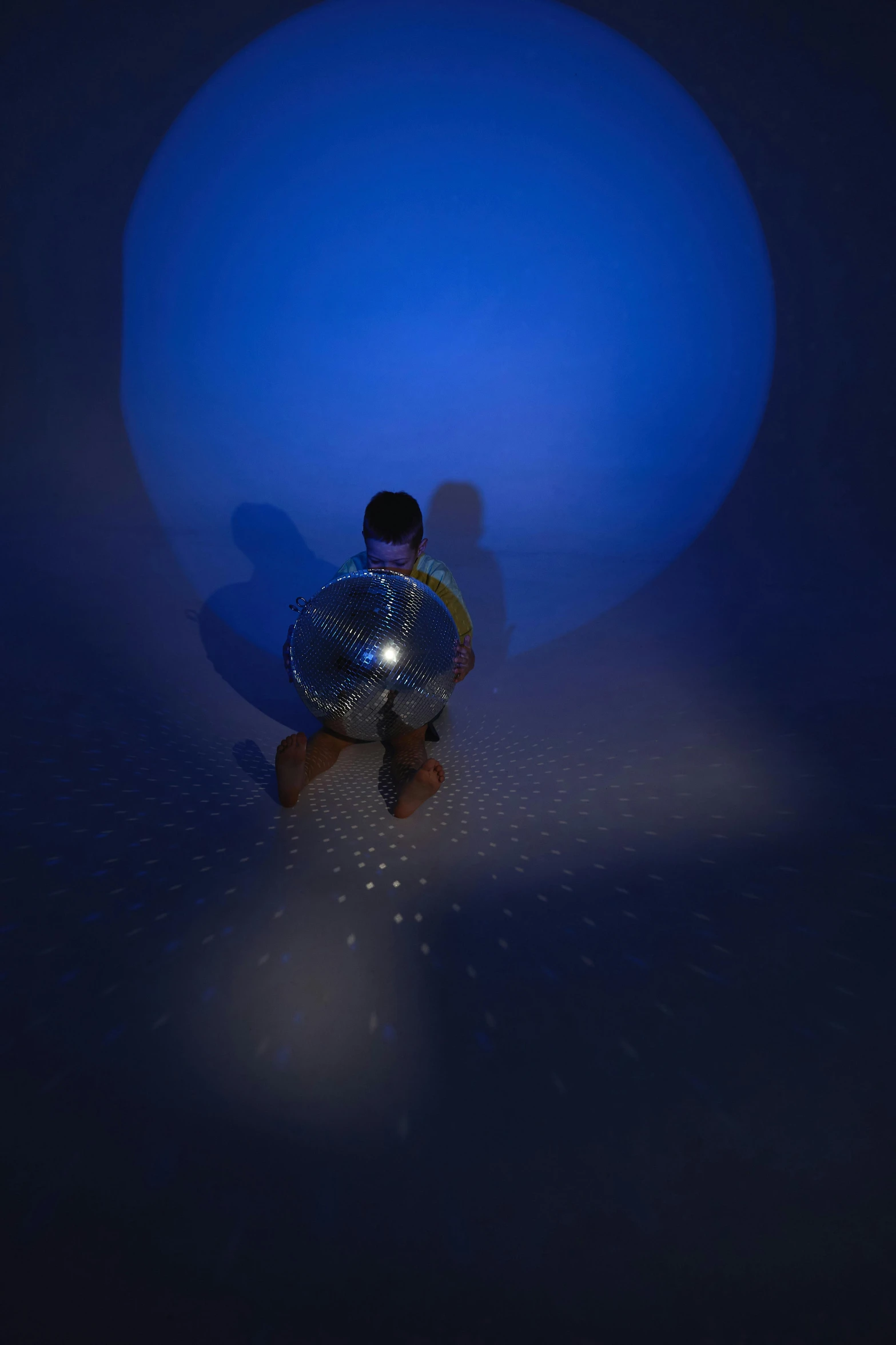 a boy sitting in front of a blue ball