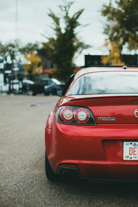 the back end of a red car sitting on the pavement