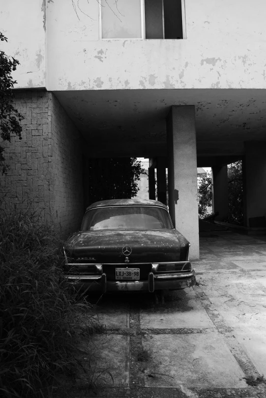 a black and white picture of a car in an otherwise empty parking garage