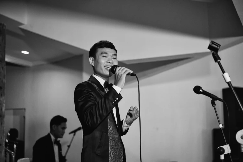 an asian male singer holding a microphone and singing