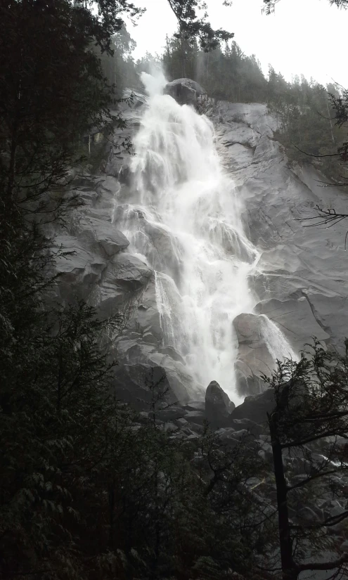 the man is sitting by the waterfall in the rain