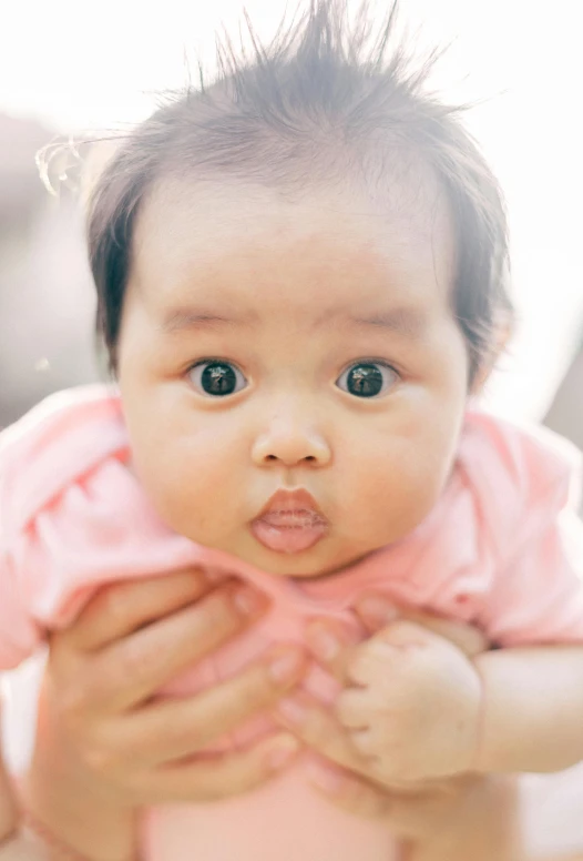 a baby with long black hair sitting on the ground