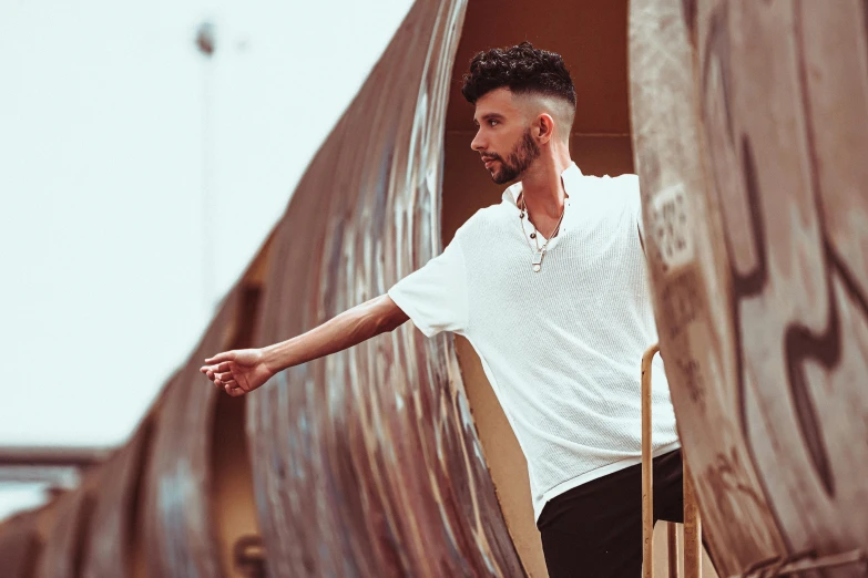 a man with a beard and a short black beard stands on a wooden ramp wearing white shirt