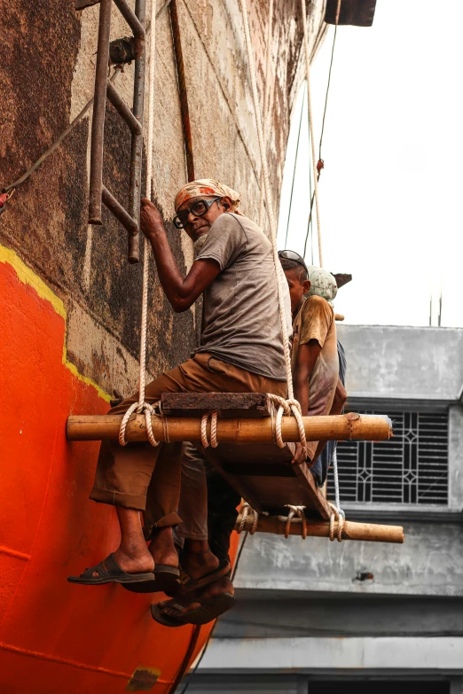 two men are hanging on to the side of a building