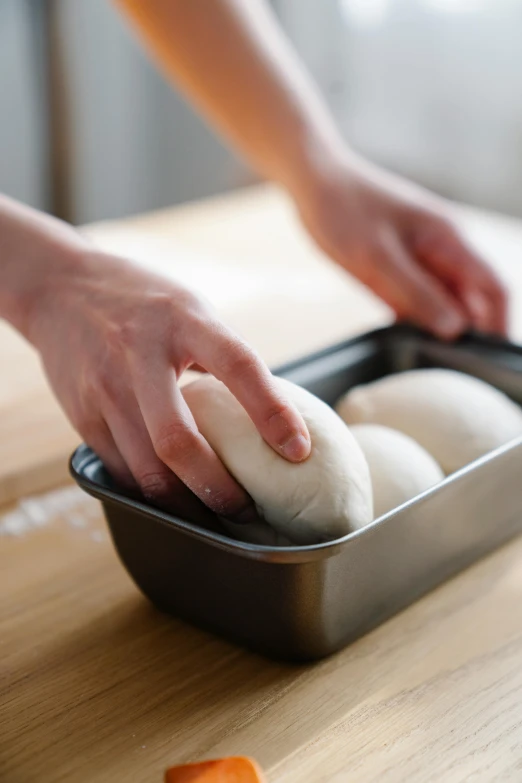 a person putting dough in a pan on a counter