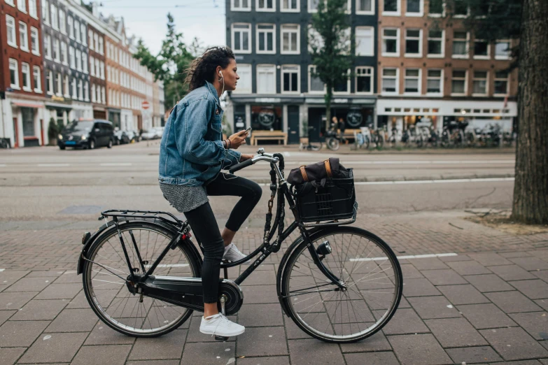 a woman in denim jacket sitting on bicycle