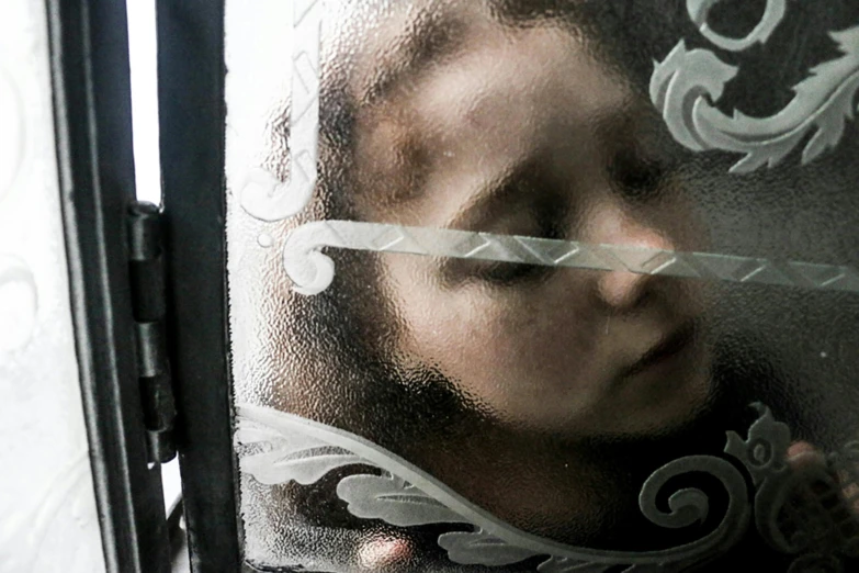 a baby looking out of a window with frost