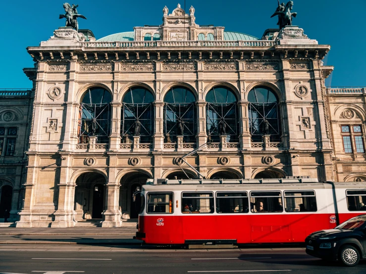 a white and red city bus parked next to a large building