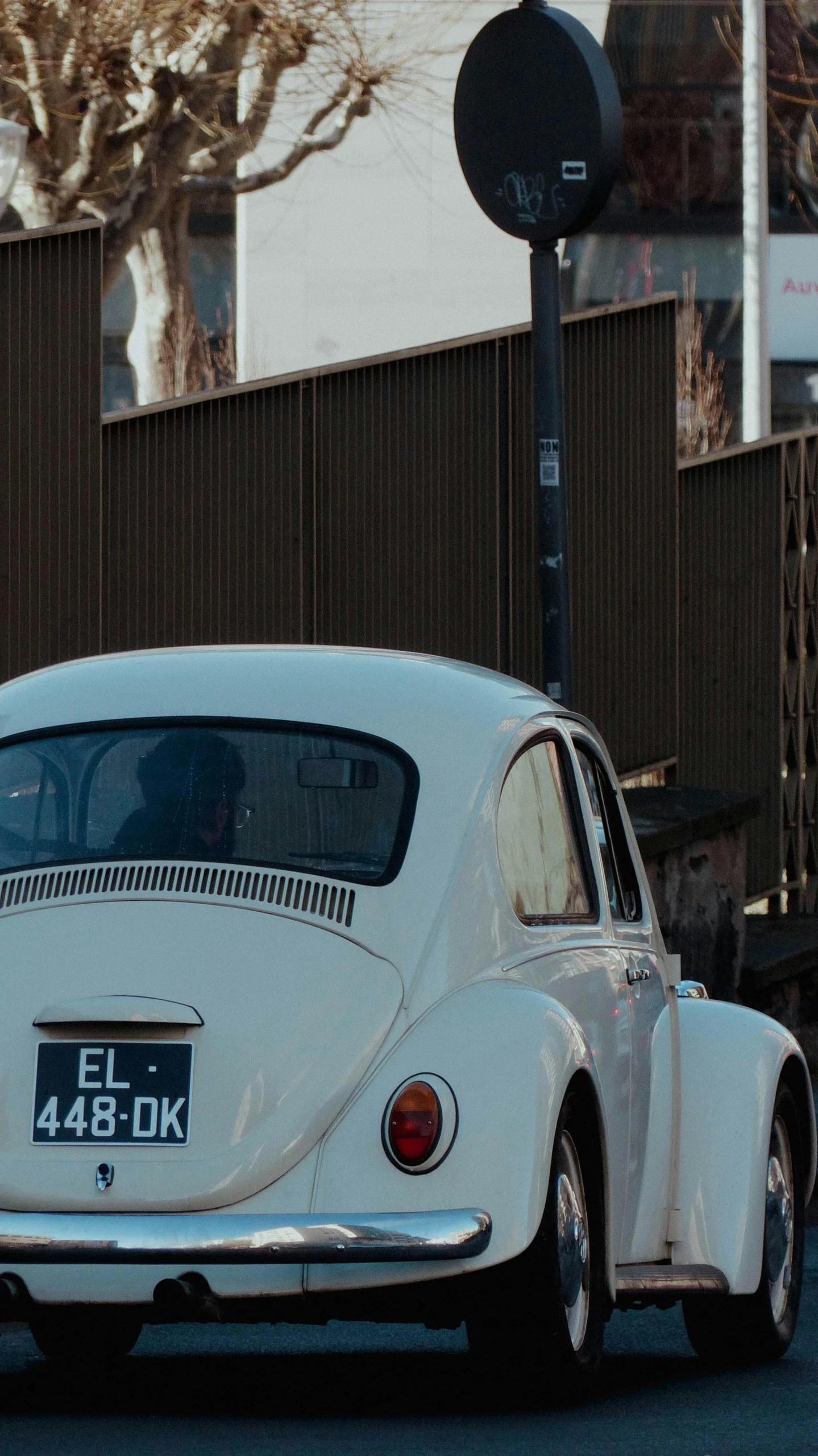 a white vw bug drives down the street