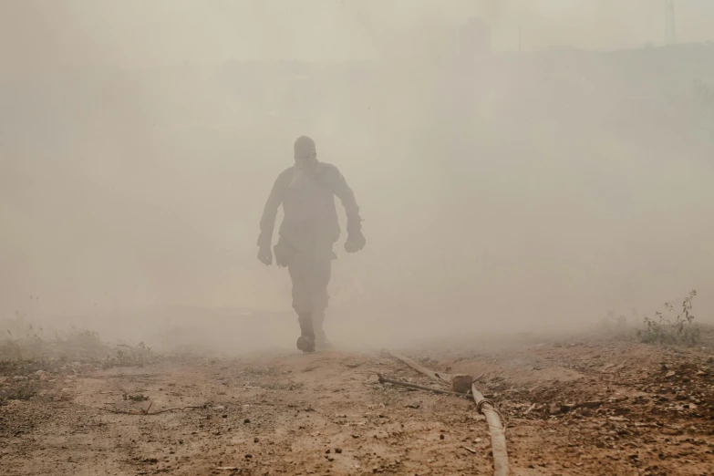 a man walking through the dust in the desert