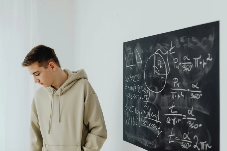 a man leaning against a wall with a blackboard in the background