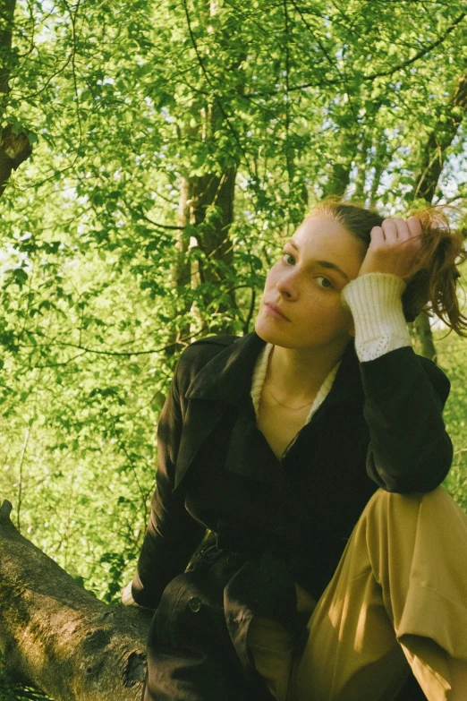 a woman sitting on a tree nch holding her hair in the wind