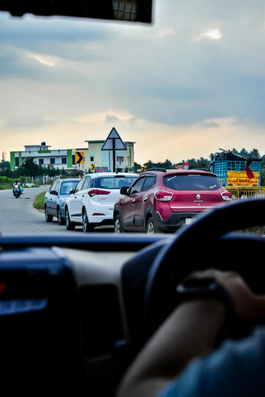 a view of a road with cars, buildings and a sign behind it