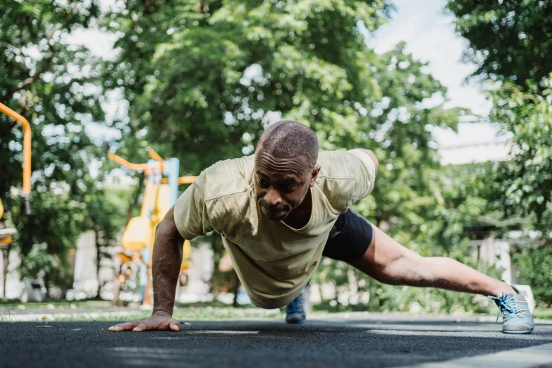 a man in yellow shirt doing h ups on pavement