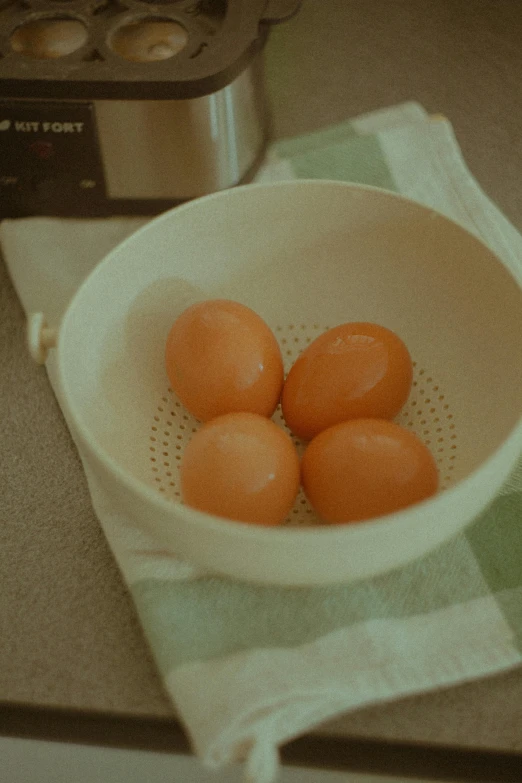 small group of four orange eggs sitting in the bottom of a white bowl