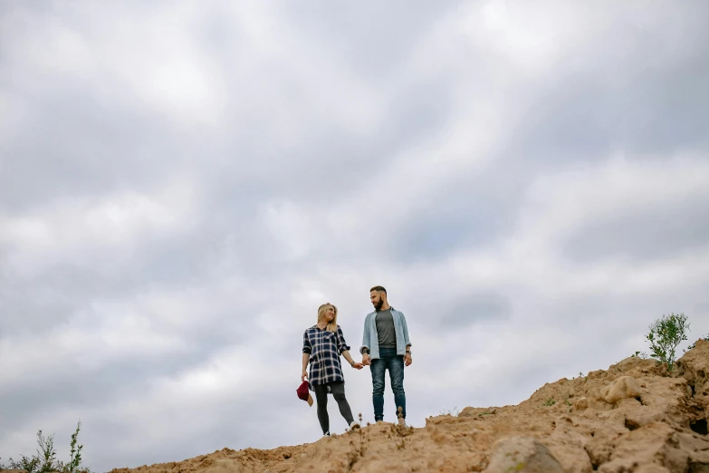 a man and woman walking on top of a hill