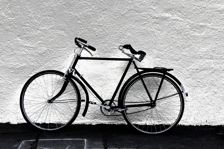 a bike parked against a wall by the pavement