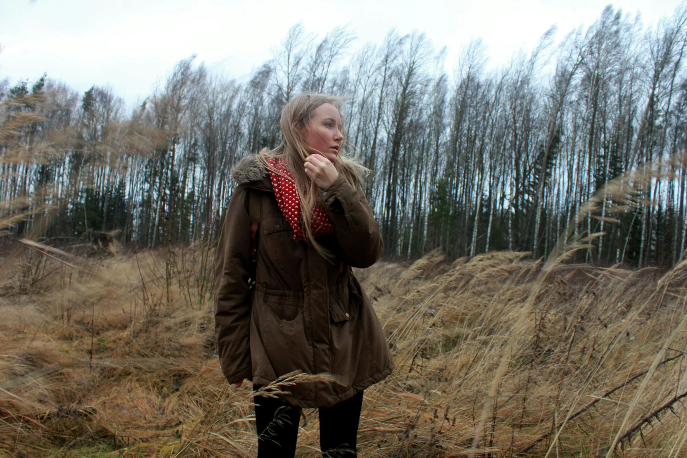 a girl wearing brown winter clothes while eating food in a field