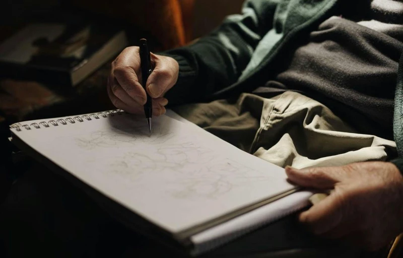 a person sitting in a chair drawing with a pen