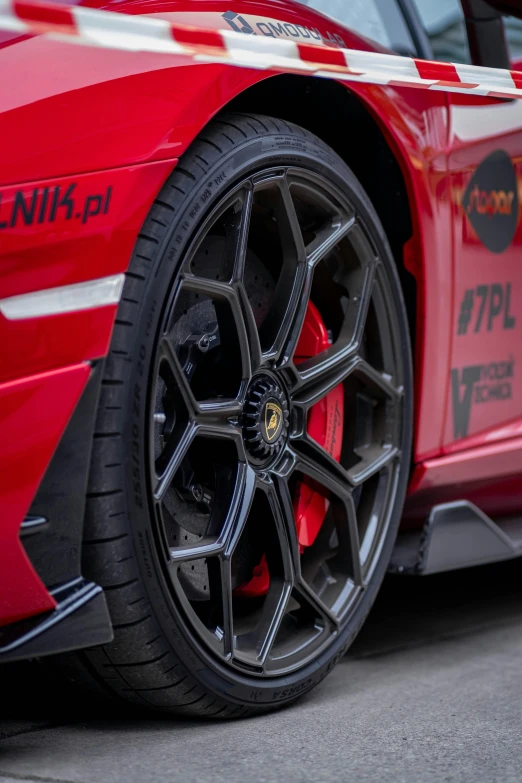 a red car with a large black tire and some red tires