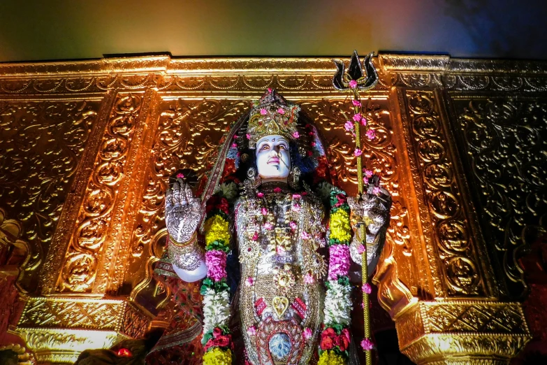 god standing among gold and flowers with a lit background