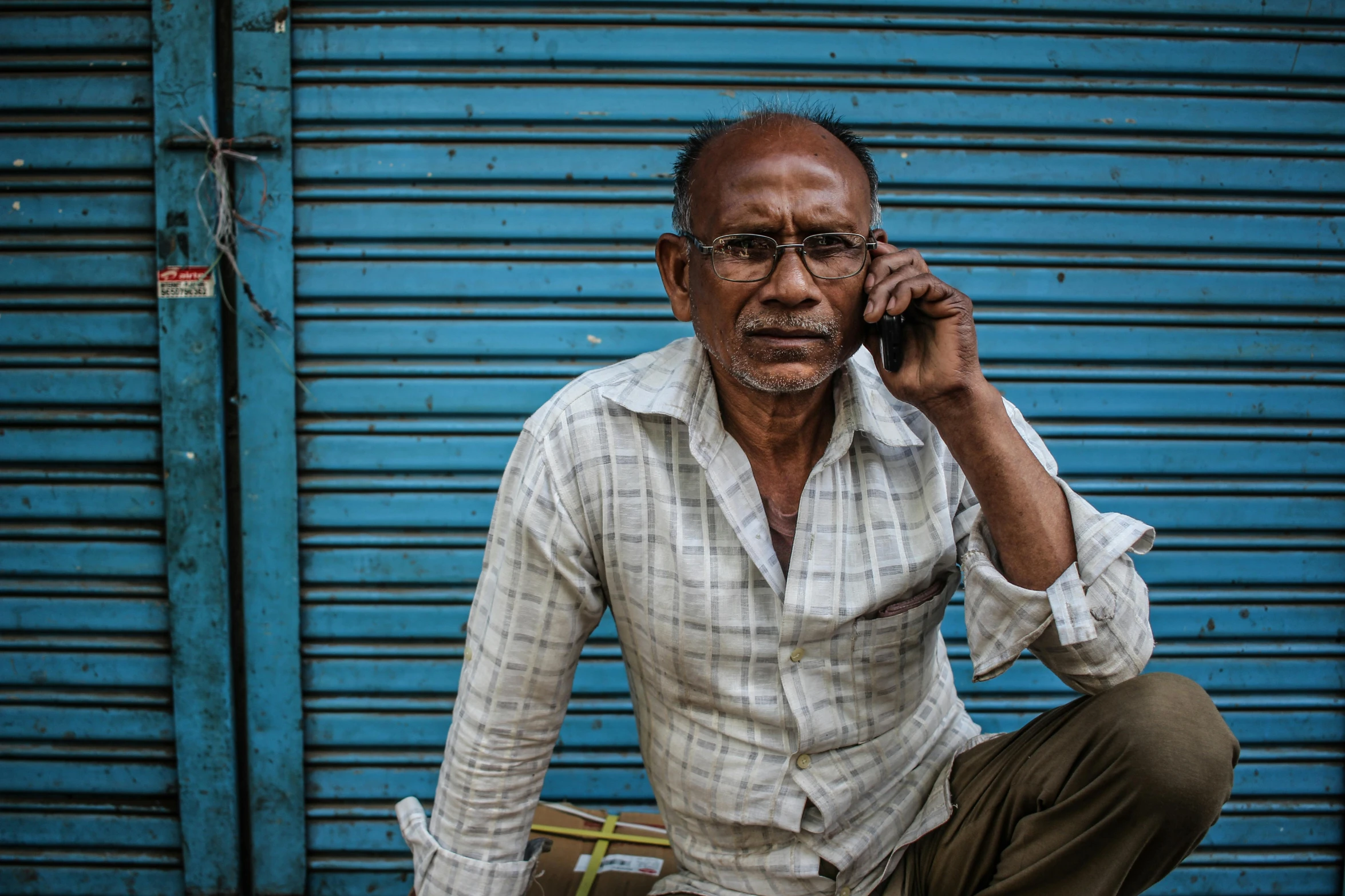 an old man sitting down on his cell phone