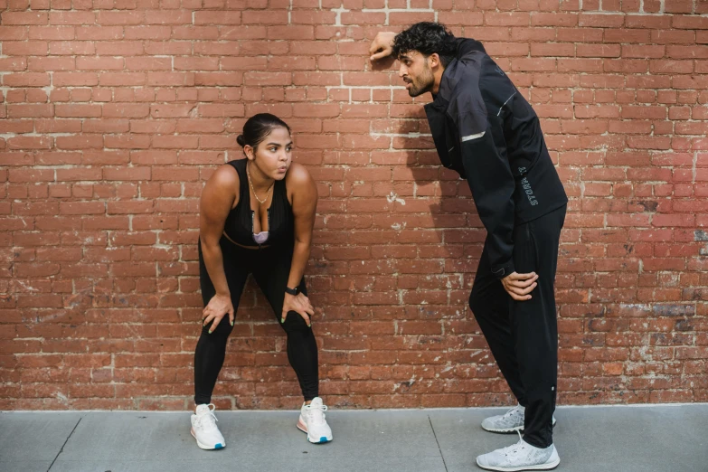 a man and woman stretching by a brick wall