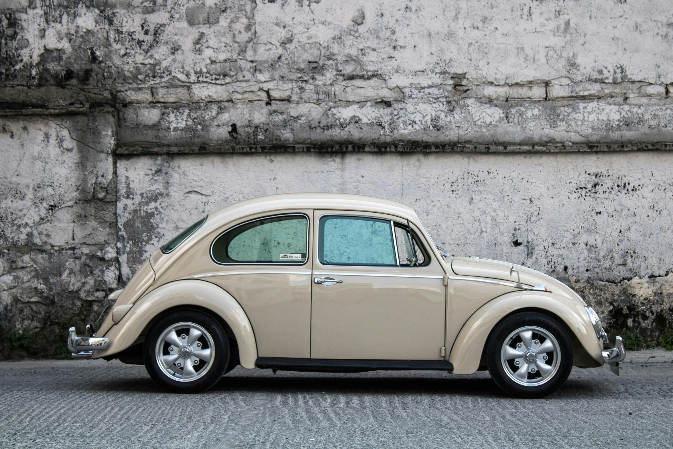 an old, beige car sits parked in front of an old building