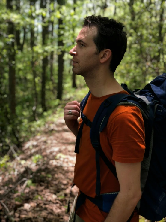 a young man hiking in the woods wearing a backpack