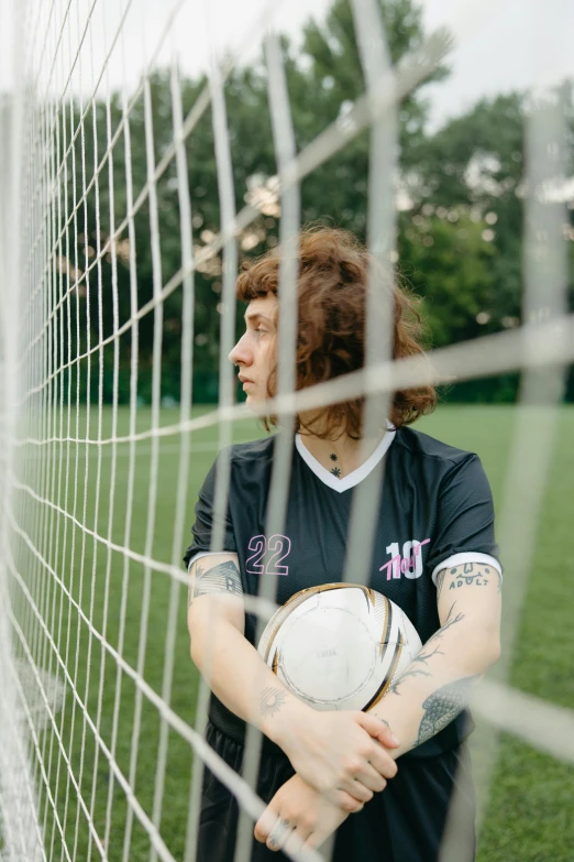 a woman holding onto her soccer ball in front of a net