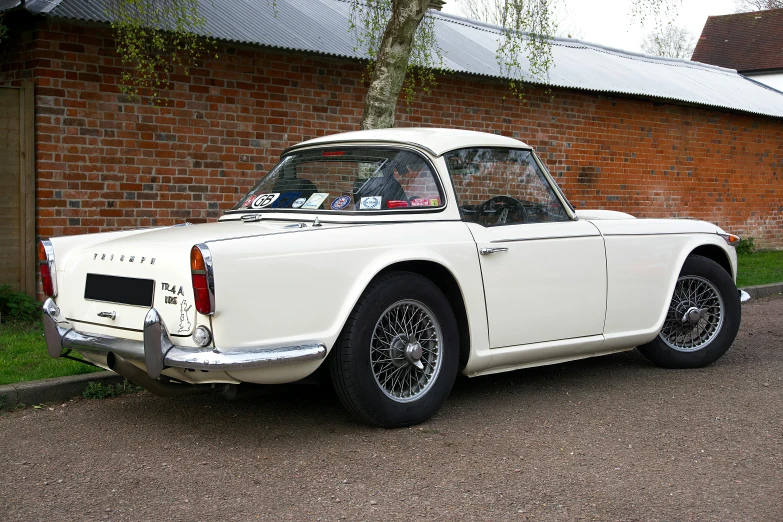 an old fashioned white car is parked on the side of the road