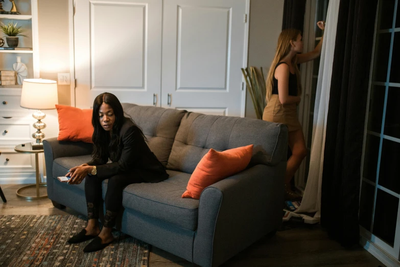 woman sitting on gray couch in living room with mirror behind her