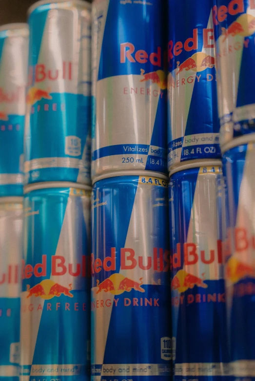 a row of red bull soda cans on a shelf