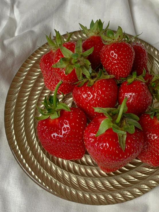 the strawberries are placed on a golden dish