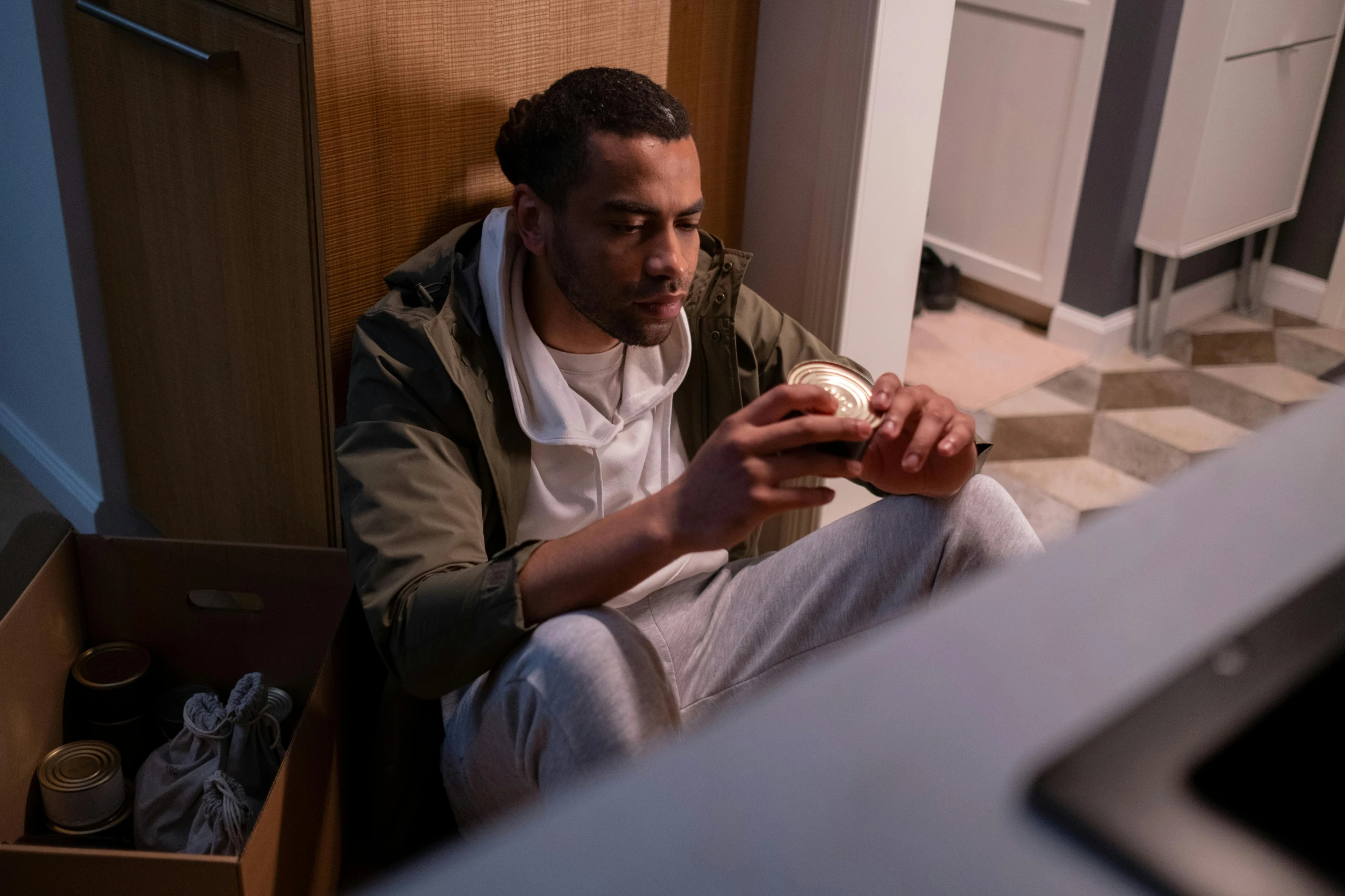 man sitting on floor eating food from cup