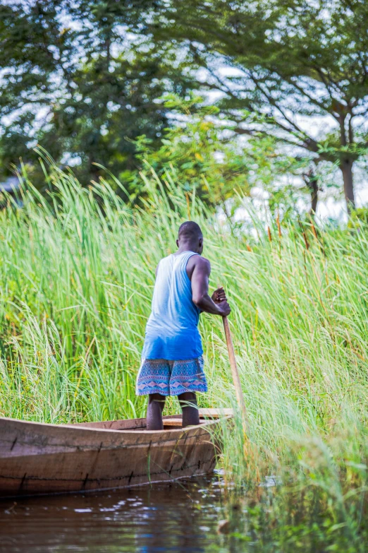 boy on boat in grass land, facing water