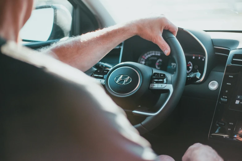 a man in a car is seen with his hands on the steering wheel