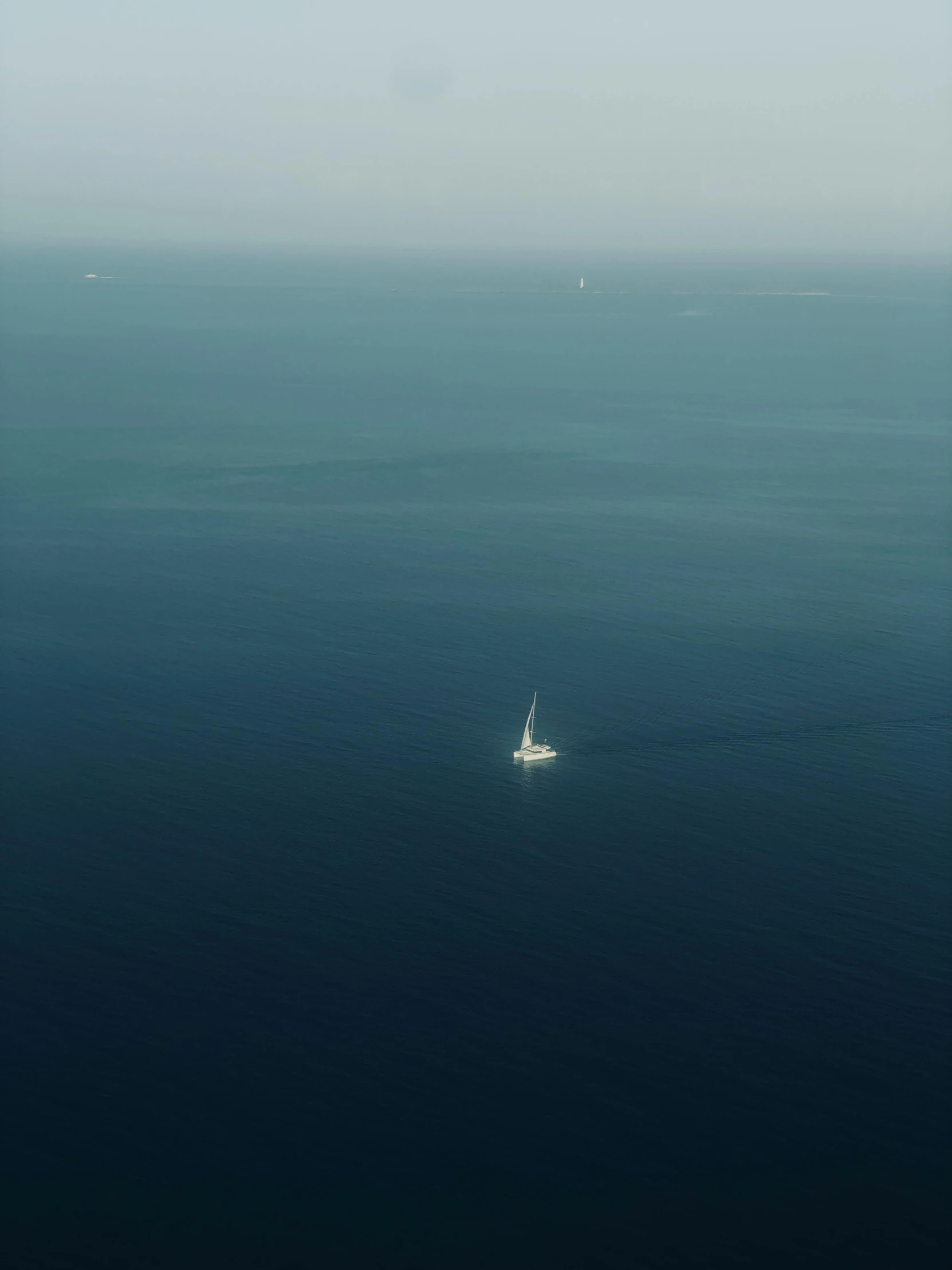 a sail boat floating in the ocean near the shore