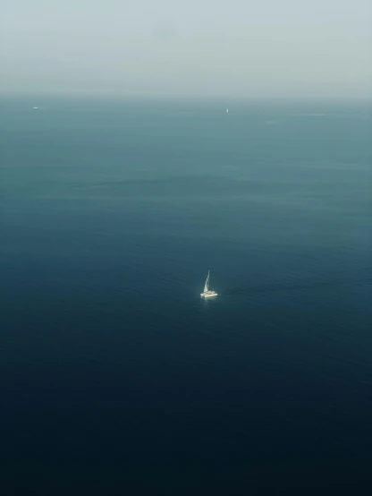 a sail boat floating in the ocean near the shore