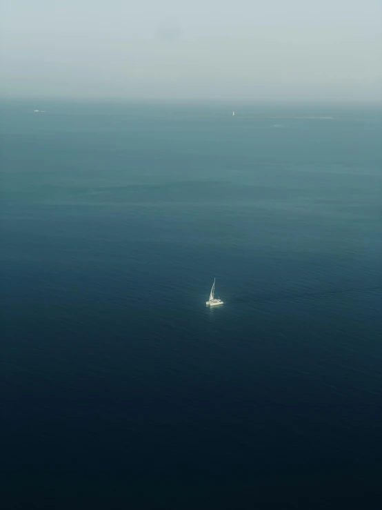 a sail boat floating in the ocean near the shore