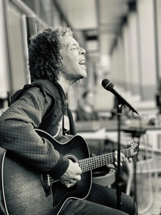 a man holding a guitar singing into a microphone