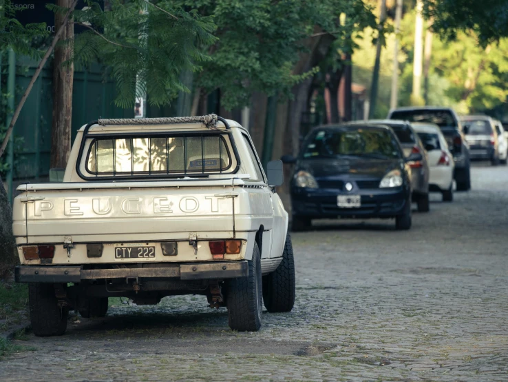 a truck sitting in the street next to trees and other cars