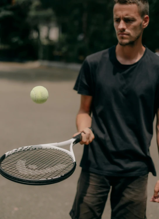 a man standing on a street holding a tennis racquet