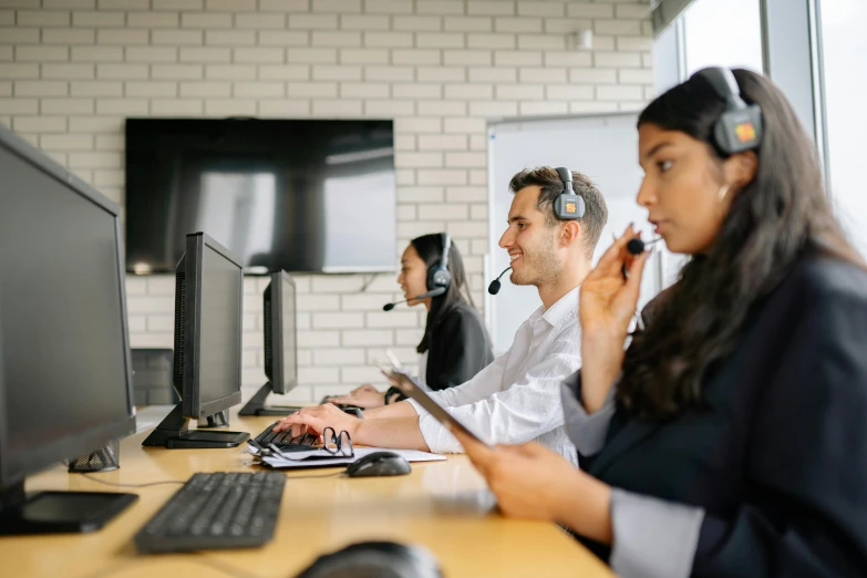 people sitting at desk talking and laughing around computer monitors