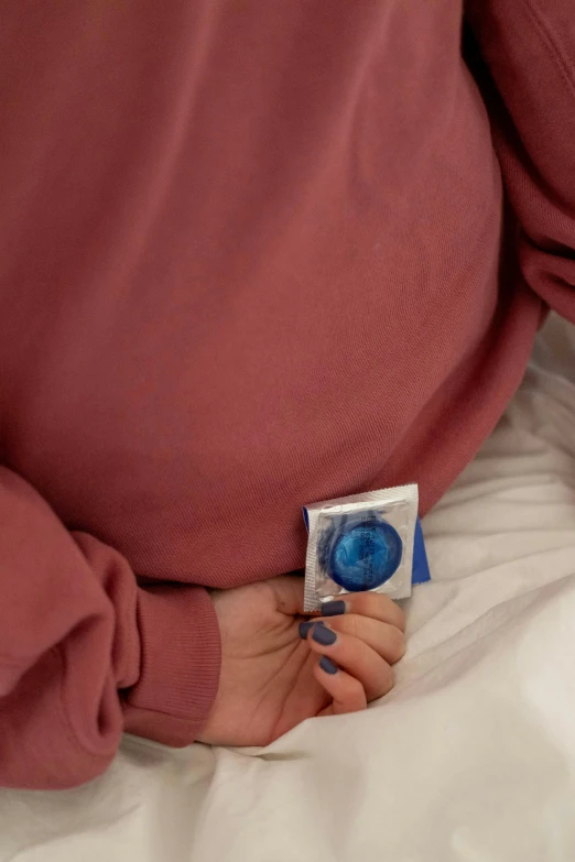 a person wearing a pink sweatshirt and holding a small item in their hand