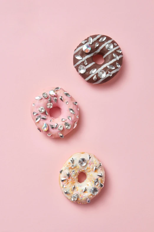 three doughnuts sitting next to each other on a pink surface