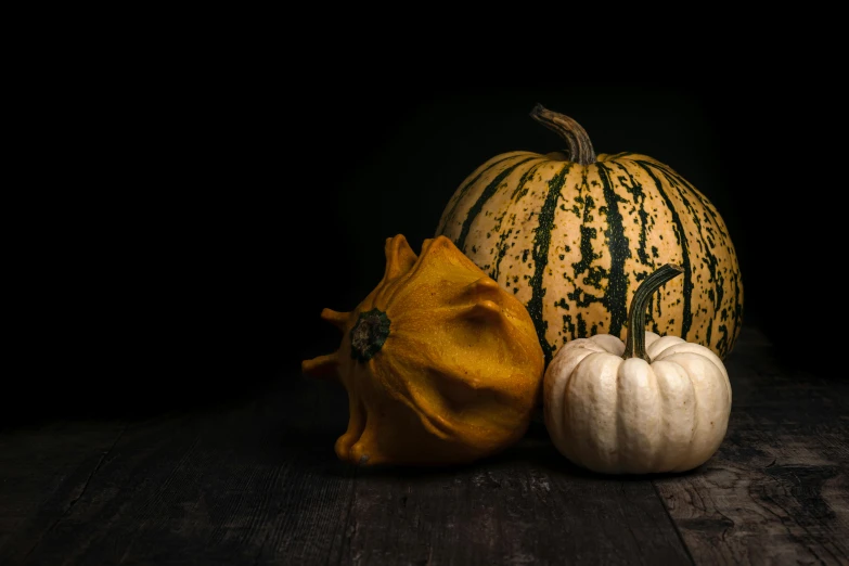 three small pumpkins are on the wooden table