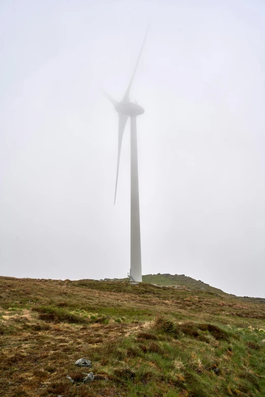 a wind farm in a foggy day on a mountain with a large windmill